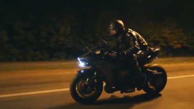 Miğferli genç adam şehir caddesinde modern siyah spor motosikletle hızlı gidiyor. Motosikletli, boş yolda motosikletiyle yarışıyor. Bisikletli adam. Özgürlük ve hobi kavramı. Kapat.