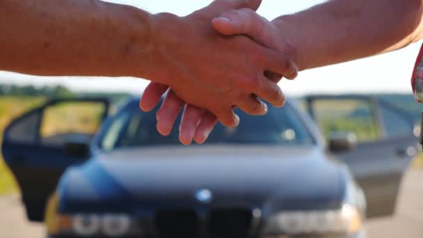 Handshake between salesman and new owner of automobile after successful deal. Seller congratulating buyer on purchase. Shaking of male arms outdoor. Slow motion Close up — Stock Video