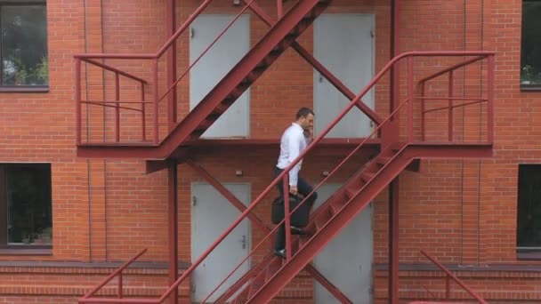 Podnikatel stoupá po schodech do obchodního centra. Důvěryhodný muž ve slavnostním obleku s taškou, který kráčí po schodech a telefonuje. Dělník dojíždí do práce v úřadu. Koncept úspěšné kariéry — Stock video