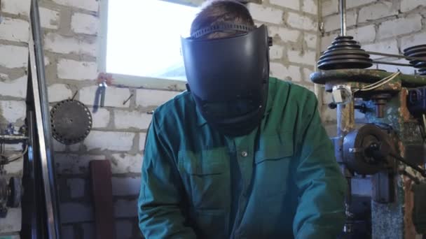 Professionele reparateur in beschermende masker werken met metalen details in de werkplaats. Mannelijke monteur in werkkleding doet zijn werk in de garage. Concept van onderhoudsdienst. Sluiten Slow motion — Stockvideo