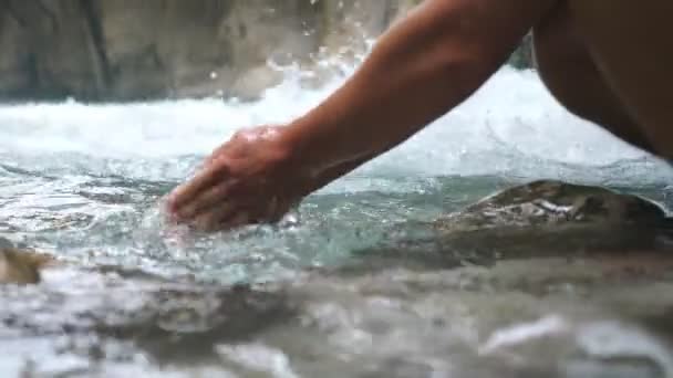 Tanınmayan yürüyüşçü, dağ nehrinde ellerini temiz soğuk suyla yıkıyor. Nehrin ortasında hızlı ve ferahlatıcı bir şekilde duran adam. Seyahati sırasında erkek turist. Arka plan bulanık. Yavaş çekim — Stok video