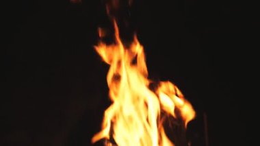 Mangalda gece yanan odun ve kömürden parlak alevler yükselir. Siyah arka planda yakacak odun ve kömür yanıkları. Sıcaklık ve sükunet kavramı. Yavaşça kapat.