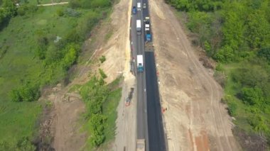 Yenilenme kırsal otobanındaki trafik akışının hava görüntüsü. İHA yol çalışması sırasında asfalt otoyol boyunca giden arabaların üzerinde uçuyor. Otomobiller kırsal alanlarda geziniyor, manzara manzaralı. Üst görünüm