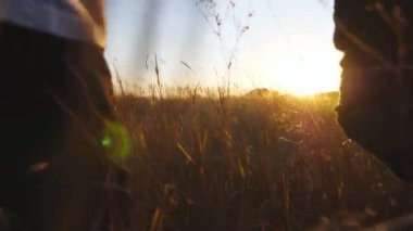 Anne ve baba ve küçük kızı gün batımında çimen tarlasında çok renkli bir uçurtmayla koşuyorlar. Küçük tatlı bir kızı olan genç ebeveynler yaz otlaklarında koşuştururken el ele tutuşuyorlar. Arka görünüm