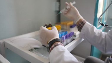 Doktor eldiven takıyor, test tüplerini sıvıyla dolduruyor. Şırınga kullanıyor ve tıkırdatıyor. Sıhhiye COVID-19 analizlerini kontrol ediyor. Erkek hekim laboratuvarda çalışıyor. Corona virüsü salgını konsepti. Kapat..