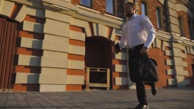 Şehir caddesinde koşan evrak çantalı genç bir iş adamı. Başarılı bir yönetici kaldırımda koşarken saatine bakar. Ofis çalışanı toplantıya geç kaldı. Erkek girişimci işe gitmek için acele eder. Dolly vurdu..