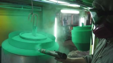 Güvenlik işçileri metal parçaları boyar. Boyacı, boya tabancasından boya püskürterek boyayı boyama odasında detaylandırıyor. Endüstriyel imalatta çalışan teknisyen. Elle püskürtme. Yavaş çekim. Yakın çekim..