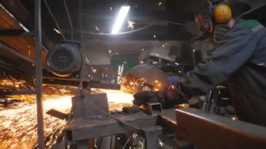 Endüstriyel işçi metal tüpü kesmek için testere kesme makinesi kullanıyor. Otoparkta çeliği öğüten dairesel testereli koruyucu giysili bir adam. Metal kesen bir adam. Metalden kıvılcımlar çıkar. Dolly vurdu..