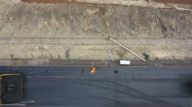 Paver Building Highway 'deki işçilerin hava görüntüleri. İnşaat ekibinin üzerinde uçan İHA yeni asfalt yol yapıyor. Yol çalışması sürecinin üst görüntüsü. Otoyol bakımı ya da onarımı. Endüstri kavramı.