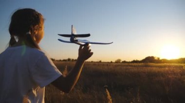 Tasasız küçük kız gün batımında çim çayırında uçakla oynuyor. Tarlada oyuncak yürüten ve uçak fırlatan tatlı bir kız çocuğu. Küçük çocuk doğada dinleniyor. Çocukluk rüyası.
