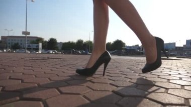 Yüksek topuklu ayakkabılı kadın bacakları şehir caddesinde yürüyor. Şehirdeki yüksek topuklu ayakkabılı genç iş kadınının ayakları. İşe giden bir kız. Yavaş çekim. Yakın çekim..