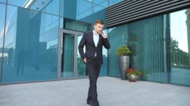 Genç işadamı telefonda konuşuyor ve şehir caddesinde yürüyor. Yakışıklı bir adam işe gidip geliyor ve dışarıda cep telefonuyla konuşuyor. Takım elbiseli adam dışarıda iş görüşmesi yapıyor. Yavaş çekim