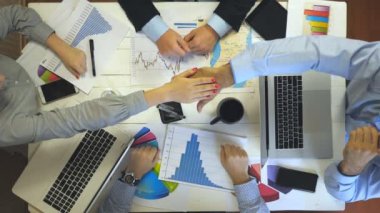 Başarı kutlayan dört iş adamının üst görüntüsü. Bir grup işveren neşe içinde tek tek kollarını birleştirdi. Modern ofiste çalışan yaratıcı ekip. Başarı konsepti.