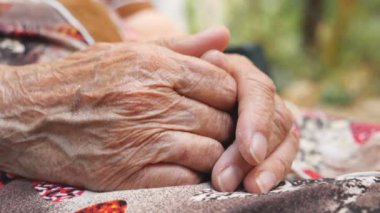 Dışarıda dinlenirken yaşlı büyükannenin ağrılı kolları. Yaşlı bir kadının kırışık elleri dışarıda. Yan Görünümü Kapat.