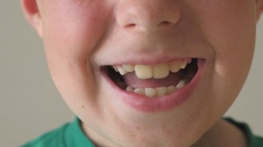 Gülümseyen genç çocuk yakın çekim. Yüzündeki mutlu ifadeyi ile yakışıklı çocuk portresi. Ayrıntı görünümü mutlu çocuk yüzünde. Ağır çekim.