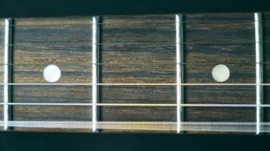 Çalma sırasında titreşimli gitar dizenin kapatın. Kordon strummed ve titreşimle görüyorum. Perde karşı titriyordu. Güzel ahşap dokulu arka plan. Müzik performans. Ağır çekim.