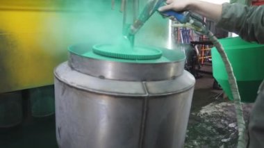 Güvenlik işçileri metal parçaları boyar. Boyacı, boya tabancasından boya püskürterek boyayı boyama odasında detaylandırıyor. Endüstriyel imalatta çalışan teknisyen. Elle püskürtme. Yavaş çekim. Yakın çekim..