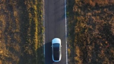 Yaz akşamları kır yolunda uçan elektrikli arabanın görüntüsü. Yeni bir SUV aracı otobanda hızla ilerliyor. Çevre dostu araba otoyol boyunca elektrik yükü ile gidiyor. Üst Görünüm Kapat.