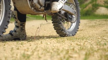 Close up wheel of powerful off-road motorcycle starting movement and kicking up dry ground or dust. Motocross bike starts movement. Concept of motorsport or active lifestyle. Slow motion Low view.