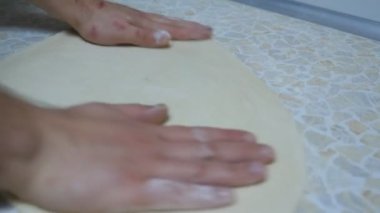 Restorandaki mutfak masasında pizza için un hamuru şekillendiren şefin ellerini kapat. Aşçının erkek kolları mutfakta ahşap bir yüzey üzerinde hamur işi oluşturuyor. Yemek hazırlama kavramı. Yavaş çekim.