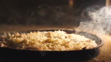 Lezzetli dört peynirli pizza mutfak restoranında elektrikli fırında pişiyor. Mozzarella, çedar, parmesan peyniri ve fırında eriyen feta. Yemek hazırlama süreci. Kapat..