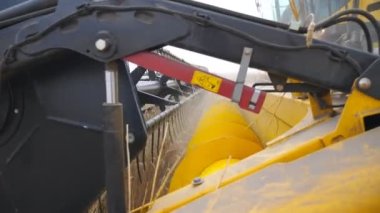 Close up knife of combine spinning and cutting ears of wheat. Harvester slowly riding through field and gathering crop of ripe barley. Concept of food industry or harvesting. Slow motion Detail view.