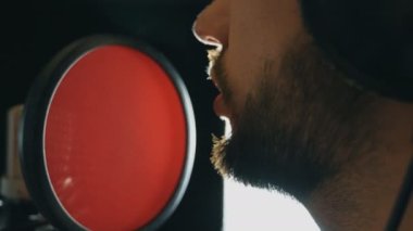 Erkek şarkıcı şarkı ses stüdyosunda ağzı. Tanınmayan adam kayıt yeni şarkı. Sakallı adam mikrofon için şarkı söyler. Yaratıcı müzisyen çalışma. Haritayı iş kavramı. Ağır çekim yakın çekim.