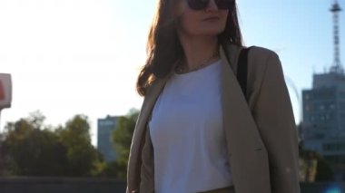 Young beautiful woman holds shopping bags going at urban street after purchases. Fashionable lady carries paper packets walking along city square. Concept of leisure, sales and discounts. Slow motion.