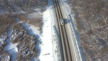 Karlı kırsal yolda giden beyaz SUV 'yi takip ediyorum. Kışın güzel kırsal yolda araba sürmek. Doğada kış tatili yolculuğu. Aile seyahati kavramı. Hava Görüntüsü Üst Görünüm.