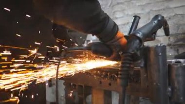Ustabaşı metal kesmek için testere kesme makinesi kullanıyor. Garajda ya da atölyede çeliği kesen dairesel testereli bir adam. Metal öğüten endüstriyel işçiler. Sıcak metalden kıvılcımlar çıkıyor. Yavaş çekim.