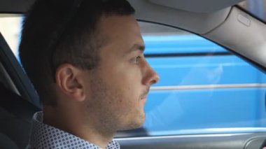 Genç işadamı city adlı araba ve konuşma gömlekli. Otomatik sürüş ve konuşurken ciddi bir yüz olan beyaz adam. Salon yan görünümden. Ağır çekim.