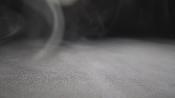 床に広がっている花瓶から濃い白煙を閉じます 表面に覆われた電子タバコやフカからのミルク蒸気の純粋なクラブ 黒の背景 低ビュースローモーション — ストック動画