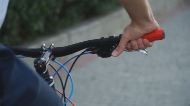 Gidonu tutan ve bisikleti süren bisikletçinin elini kapat. Bisiklete binen, vites değiştiren, tanınmamış bir erkek motorcu. Sportif adam dışarıda bisiklet sürüyor. Sağlıklı ve aktif yaşam tarzı konsepti. Yavaş çekim.