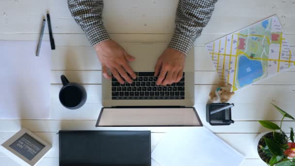 白い木製の机でノートパソコンのキーボードにテキストを入力男性の腕 ビジネスマンはペンを取り 文書にメモを取る ロフトオフィスで働いてる男 スローモーションの上で閉じる — ストック動画