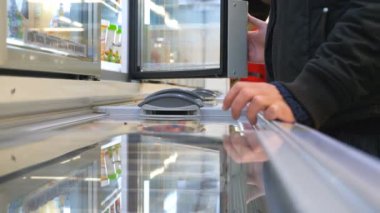 Tanınmayan bir adam buzdolabını açıyor ve dondurma alıyor ya da süpermarkette dondurulmuş yiyecekler alıyor. Marketten ürün seçen bir adam. Yiyecek dükkanından bir alıcı. Alışveriş anlayışı. Kapat..