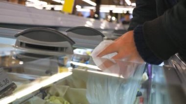 Tanınmayan bir adamın eli cam kapıyı açıyor ve süpermarketin soğutulmuş bölümünden alışveriş yapıyor. Ürün seçen adam. Müşteri buzdolabından mal seçiyor. Yiyecek dükkanından bir alıcı. Yavaş çekim.