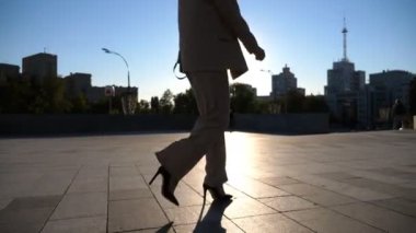 Kendine güvenen bir iş kadını işe gidip geliyor. Güneş gözlüklü güzel bayan yüksek topuklu ayakkabılarla kaldırımda yürüyor. Çekici esmer kız arka planda güneş ışığıyla şehir caddesinde dolaşıyor. Yavaş çekim