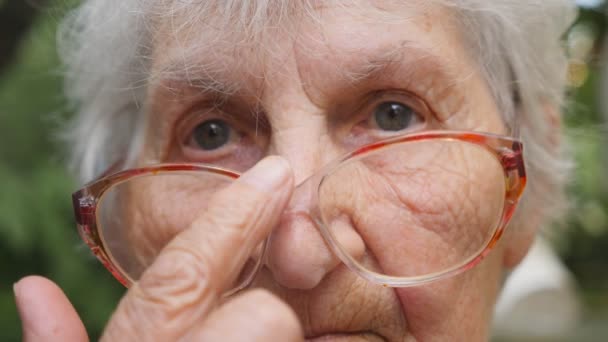 Old Woman Straightens Her Glasses Looking Camera Outdoor Portrait Sad — Stock Video