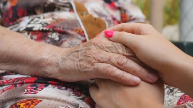 Güzel manikürlü genç bir kız dışarıda yaşlı bir kadının kırışık ellerini tutuyor. Torunumla büyükannem dışarıda vakit geçiriyorlar. Şefkatli ve sevgi dolu bir kavram. Yavaşça kapat..