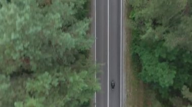 Orman yolunda motosikletli bir adam. Motosikletli, kır yolunda motosikletiyle yarışıyor. Yolculuk sırasında bisiklet süren adam. Seyahat sırasında motorcu. Özgürlük ve yolculuk kavramı. Hava Görüntüsü Üst Görünüm.
