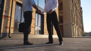 İki başarılı yönetici şehirde buluşup el sıkışıyorlar. Genç işadamı ofis binasının yanındaki ortağına siyah bir evrak çantası uzatıyor. İş anlaşması kavramı. Ağır çekim..