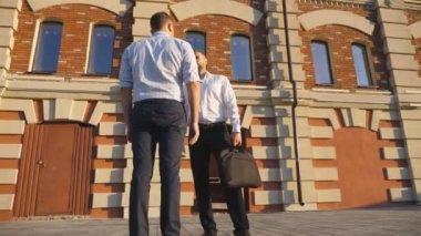 Kendine güvenen işadamları şehirdeki ofis binasının yakınında konuşuyorlar. Yöneticiler açık hava projesinden bahsediyorlar. Erkek iş arkadaşları birbirlerine sarılıp farklı yönlere gidiyorlar. Dolly vurdu..