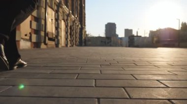 Kaldırımda yürüyen siyah ayakkabılı girişimcinin erkek ayaklarını takip edin. İş adamının bacakları şehir sokağında işe gidiyor. Evrak çantalı genç işçi işe gidiyor. İş ve finans kavramı.