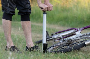 Bir bisikletçi ender bulunan eski bir bisikletten tekerlek pompalar. Ormanda bir bisikleti tamir eder..