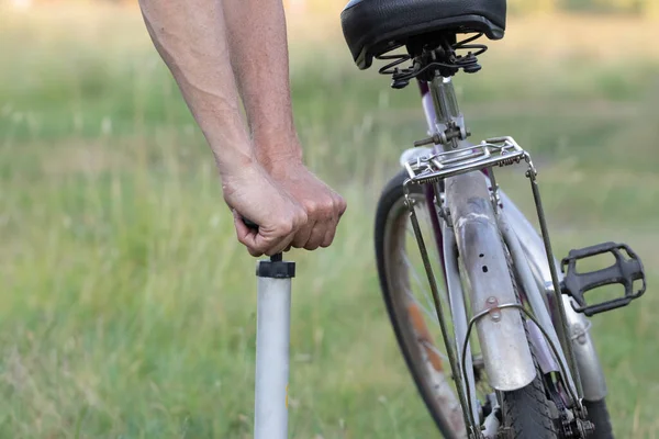 Men\'s hands inflate a bicycle wheel with an autonomous hand pump.Walk on a rare bike in the village.