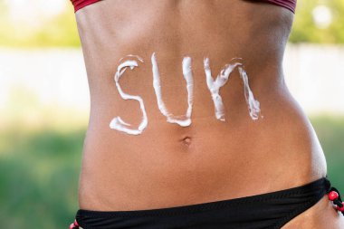 Güneşin, bronzlaşmış bir kadının midesine yazılışı. Güneş ışığı faktörü. Yaz tatili kavramı..