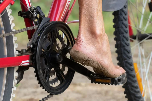 Barefoot man\'s foot in the sand on the pedal of a bicycle on the beach.The concept of summer recreation and entertainment.