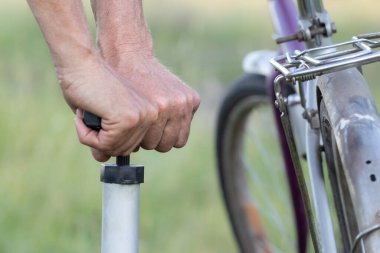 Bir adamın elleri eski bir bisikletin lastiğini otonom bir el pompasıyla şişiriyor. Yaklaş..