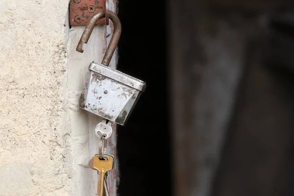 An old lock with keys hangs on a metal hinge on the wall of the barn.Country style.