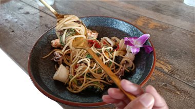 Bir kaşık ve çatal kullanarak acılı spagettiyi deniz ürünleriyle sarın..